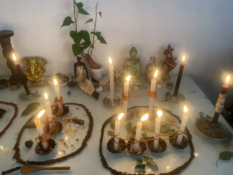 Altar com imagens de Buda e de outras tradições, e velas acesas em círculos de ervas